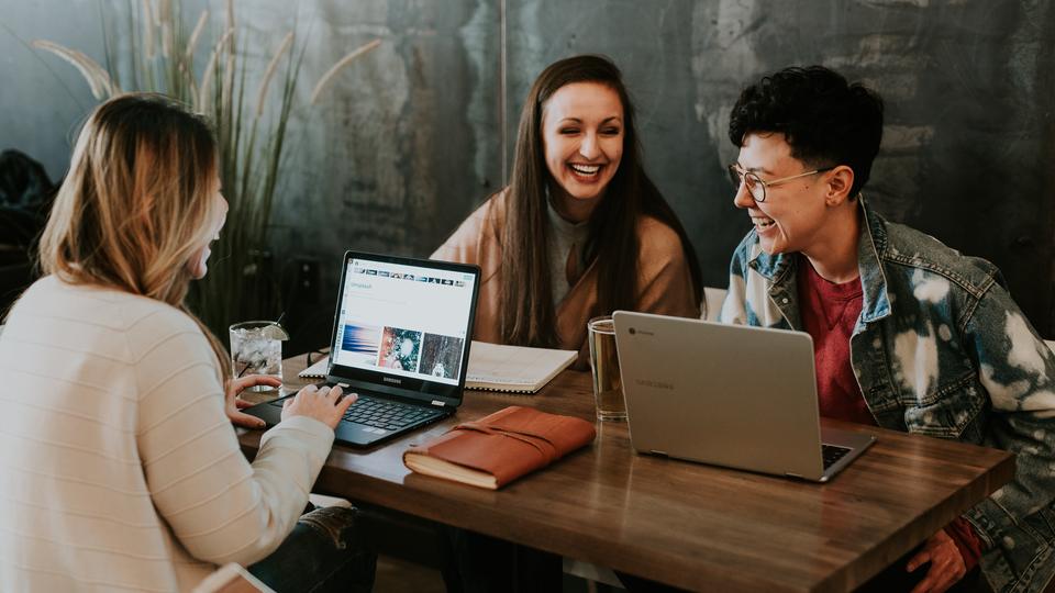 Three people talking around computers