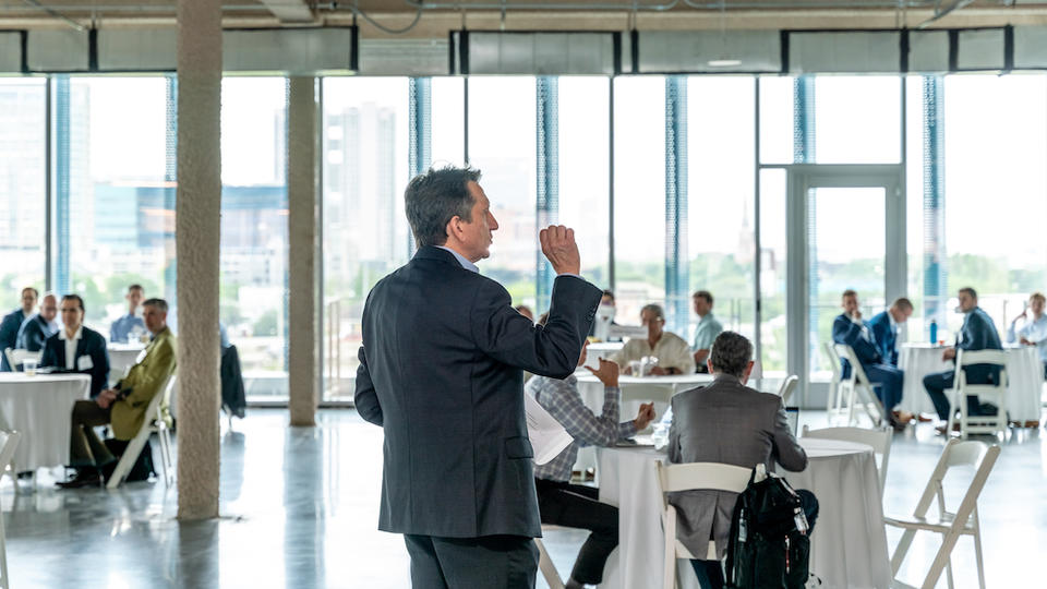 Person speaking to group of people at round tables